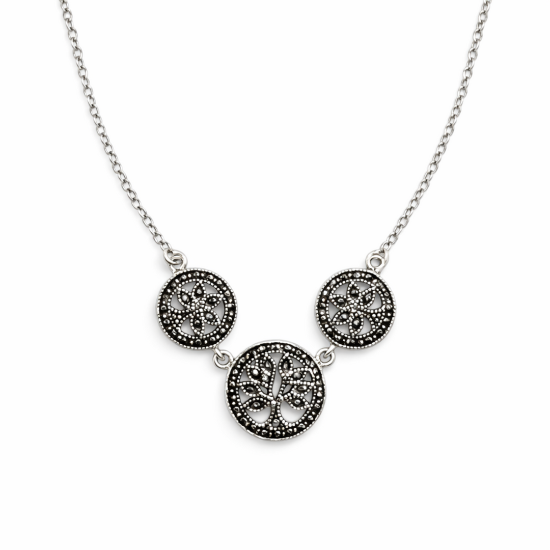 Silver necklace with three circular pendants on a white background