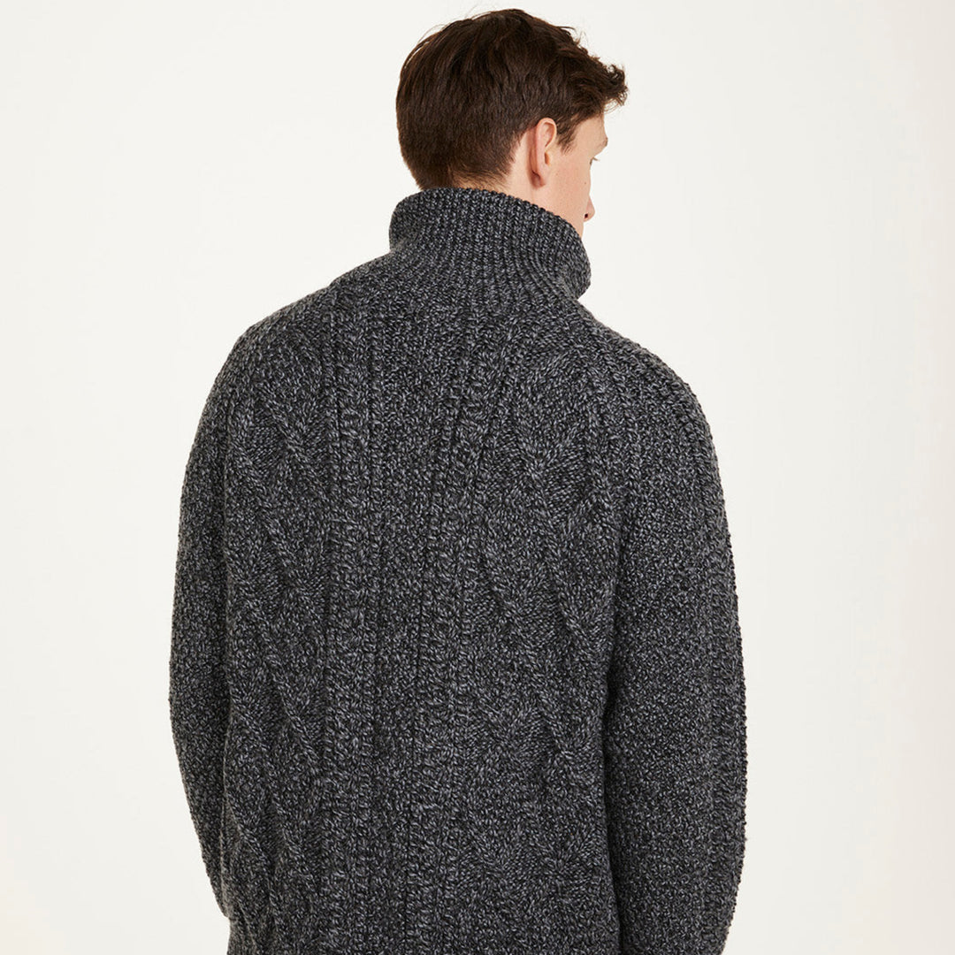 Man wearing a dark gray knitted sweater with a white background