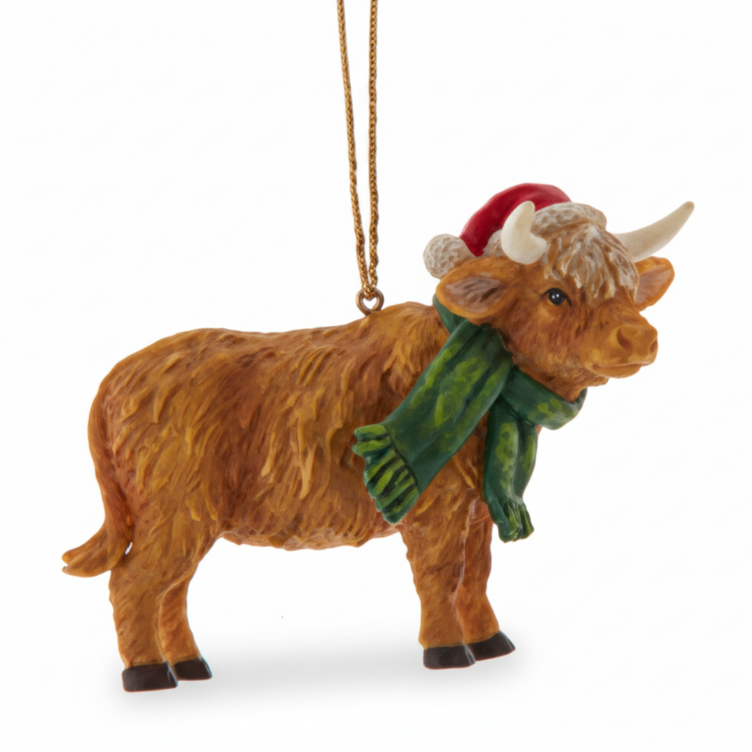 Decorative Highland cow ornament with a green scarf and red hat on a white background