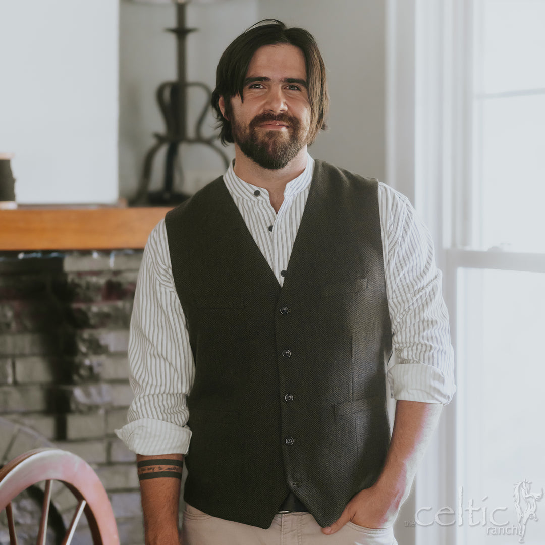 Man wearing a dark vest over a striped shirt in an indoor setting