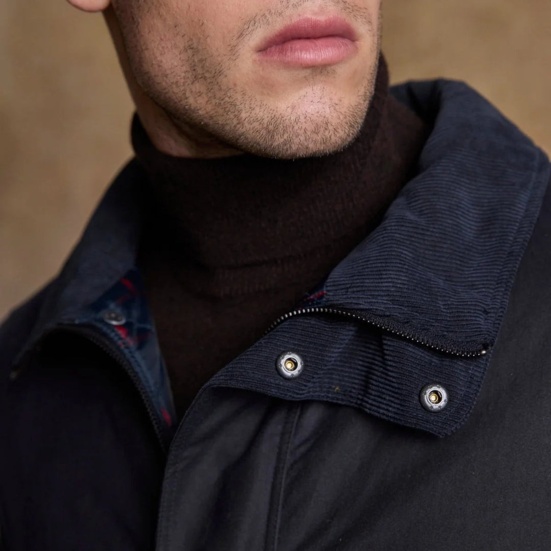 Close-up of a person wearing a dark jacket with a brown background