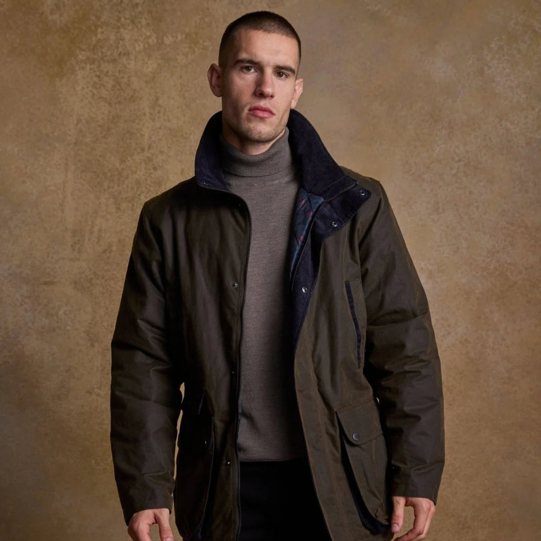 Man wearing a dark jacket over a gray sweater against a brown textured background