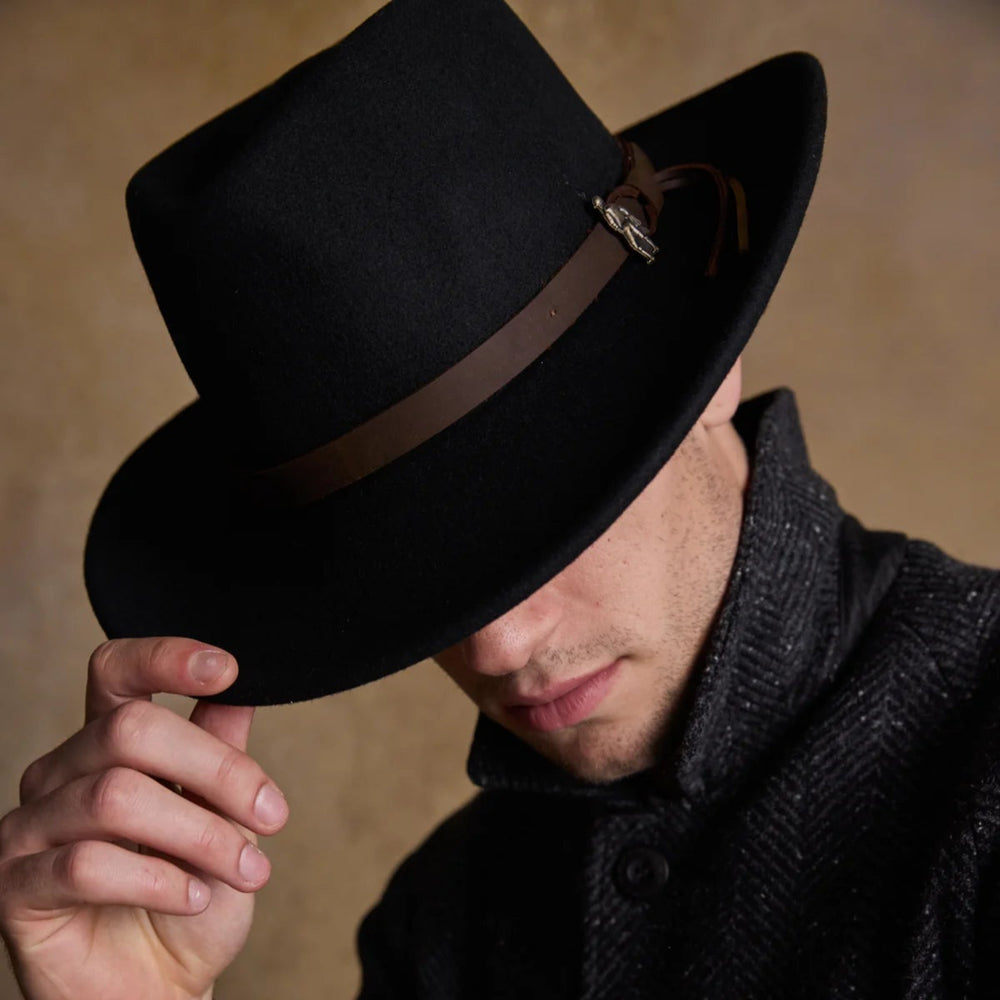 Man wearing a black fedora with a brown band against a neutral background