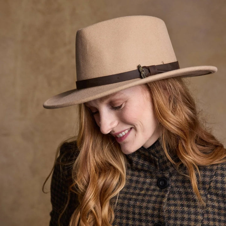 Woman wearing a beige hat and checkered coat against a brown background