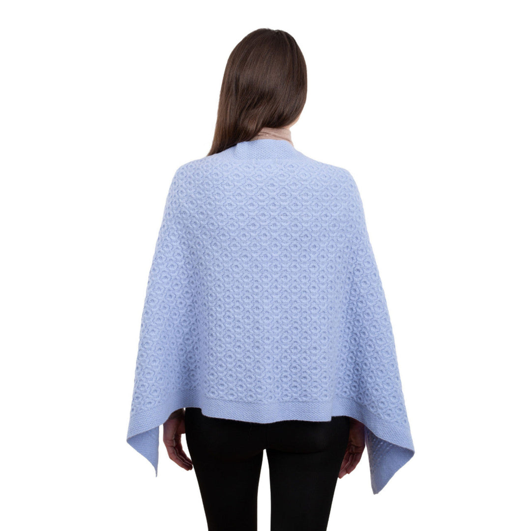 Woman wearing a light blue patterned poncho on a white background