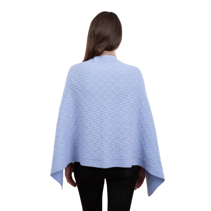 Woman wearing a light blue patterned poncho on a white background