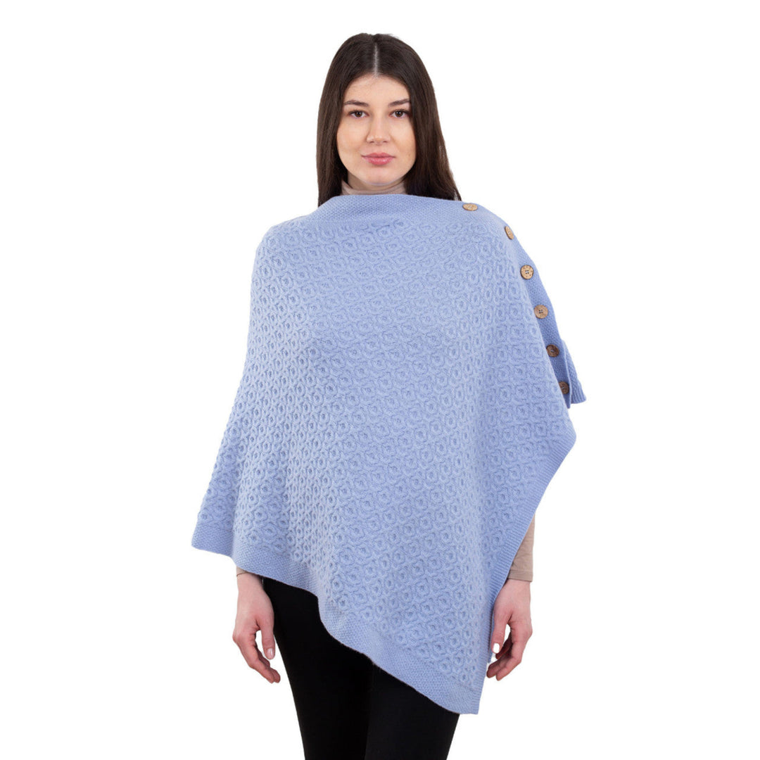 Woman wearing a light blue poncho with button details on a white background