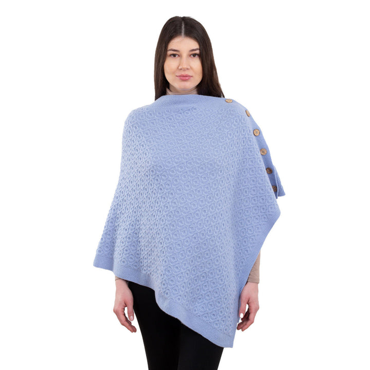 Woman wearing a light blue poncho with button details on a white background